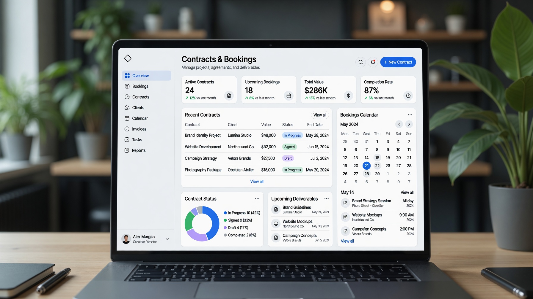 A laptop displays a professional contracts and bookings management dashboard in a creative workspace.